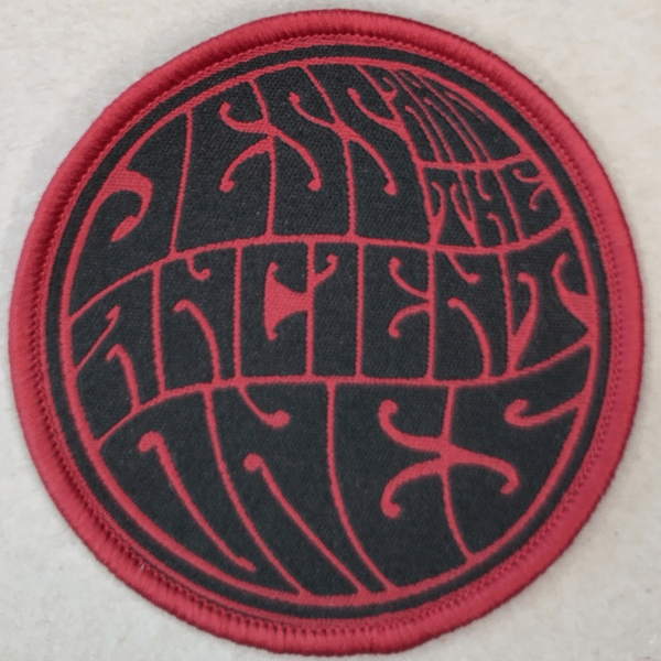 Black text Jess and the Ancient Ones on grey background. Round shaped sleeve patch item live pic.