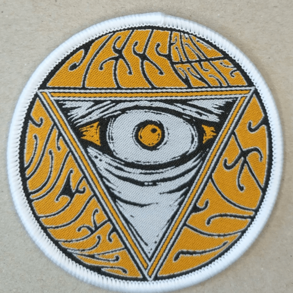 Jess and the Ancient Ones Sleeve Patch live pic with gray background, where in the middle is Yellow Eye inside of triangle pointing down. Band name around triangle. White border.